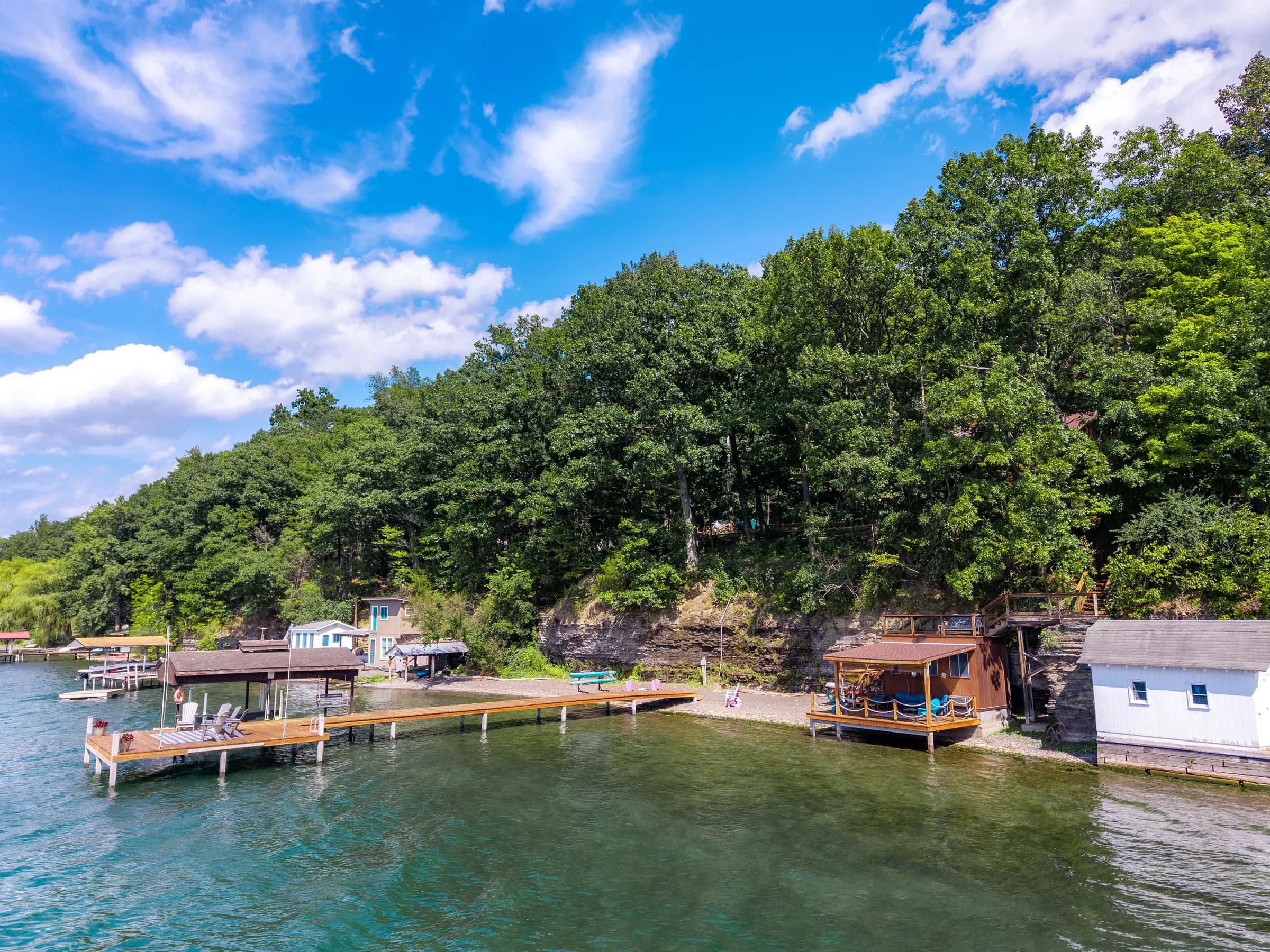 The Lakeside Landing FLX waterfront — dock, boathouse deck with Adirondack chairs, teal Seneca Lake